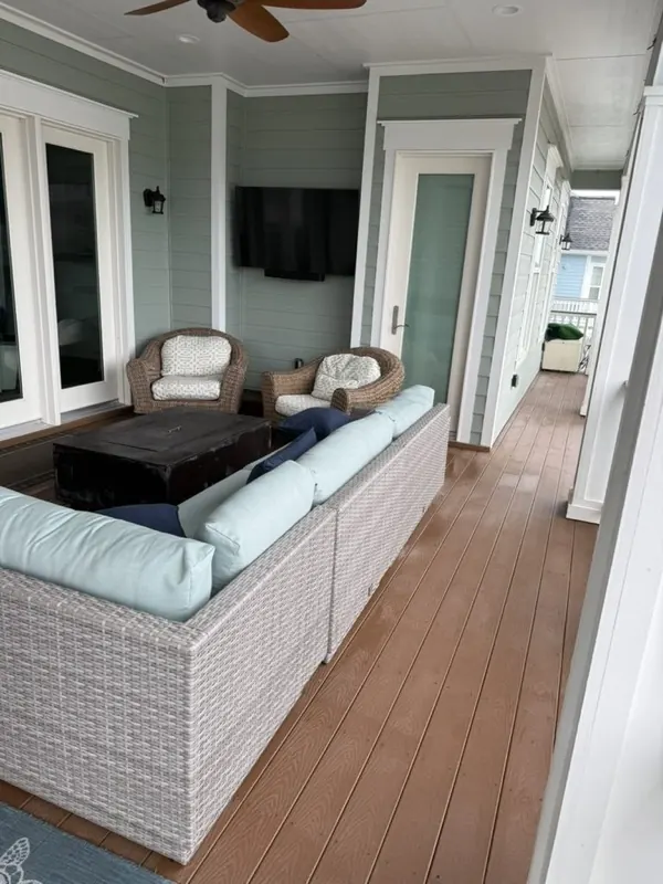 Clean covered balcony with a wicker sectional and composite deck
