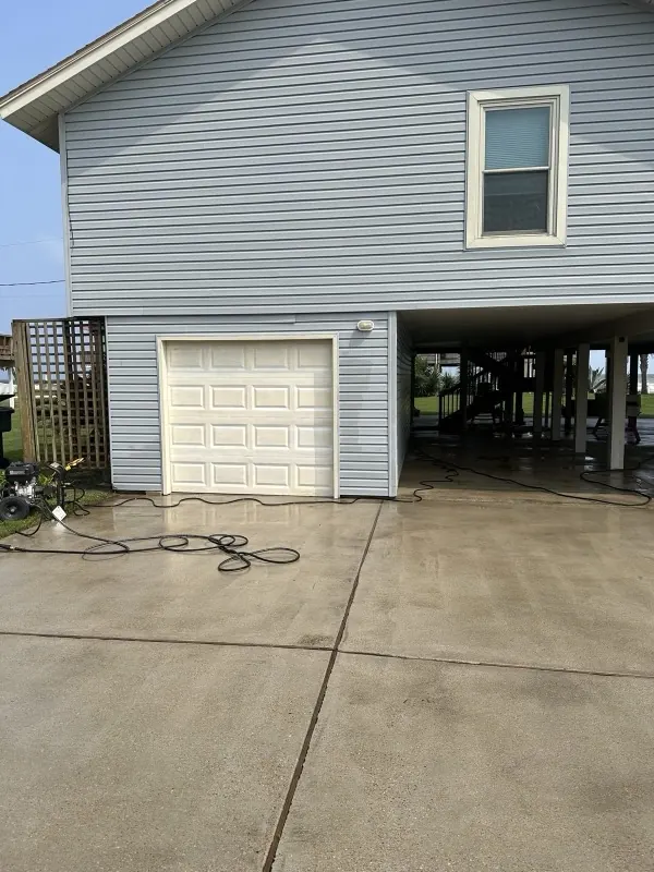 Raised blue home with a freshly washed driveway and garage