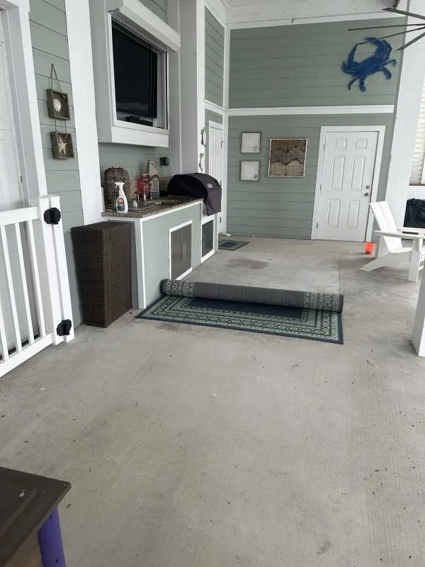 Before: dirty concrete floor at an outdoor kitchen, rug rolled up
