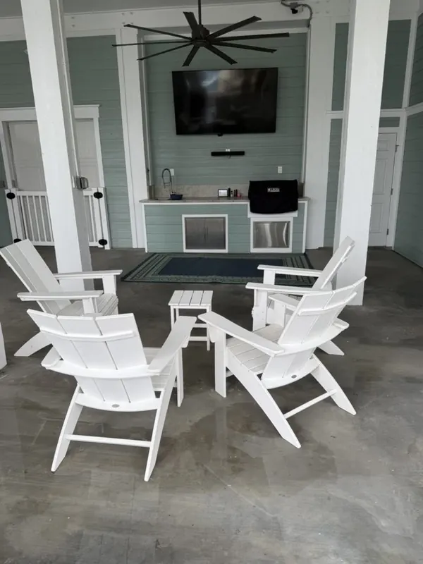 Washed outdoor kitchen patio with white Adirondack chairs