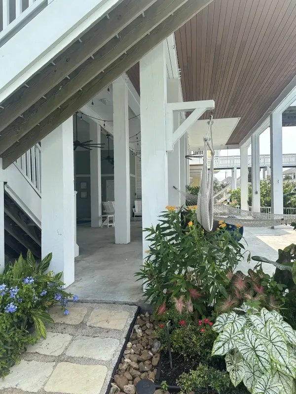 Clean under-house patio with a hammock and garden