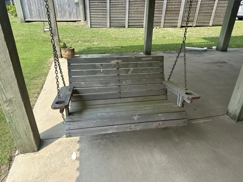 Before: weathered gray porch swing over dirty concrete