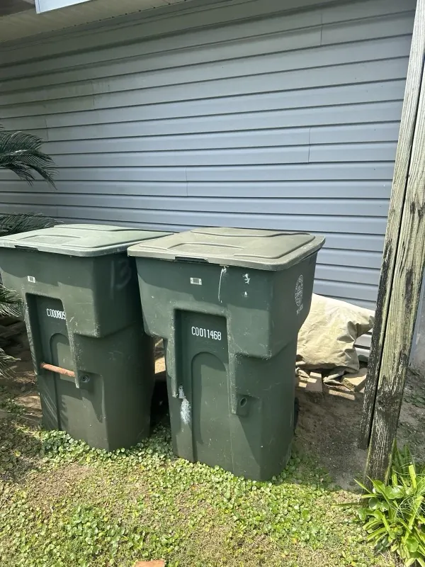 Two residential trash carts beside a Galveston home
